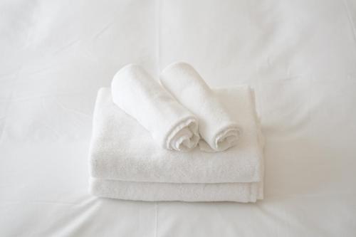 a stack of towels sitting on a bed at Hotel Otsukahouse in Tokyo
