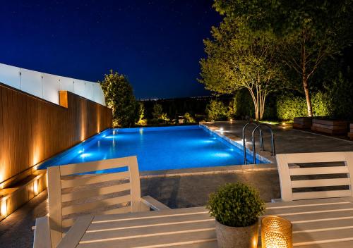 a swimming pool at night with two white chairs at Villa Magnifica - Private Pool, Elevator & Sea View in Paliouri