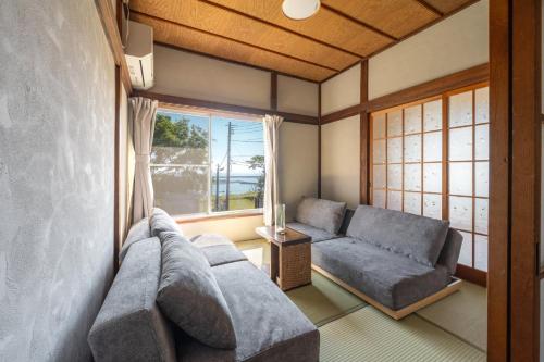 a living room with two couches and a window at オーシャンステイみうら in Miura