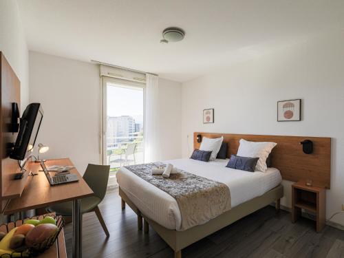 a bedroom with a bed and a desk and a window at Séjours & Affaires Grenoble Marie Curie in Grenoble