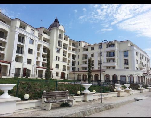 a large white building with a bench in front of it at Apartments Carpe Del Mare Complex Carpe Diem Balchik in Balchik