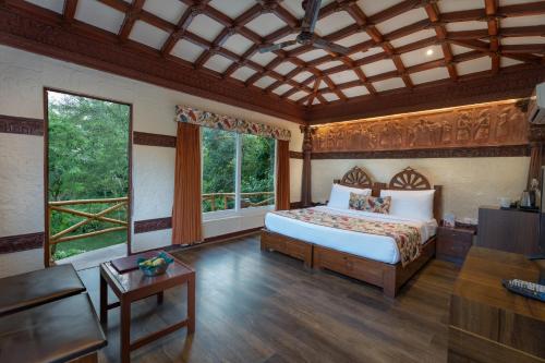 a bedroom with a bed and a large window at Summit Green Lake Tea Resort & Spa in Jakhalābāndha
