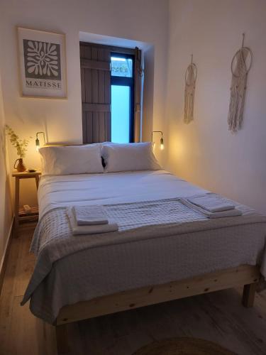 a bedroom with a bed with white sheets and a window at Casa Melro in Faro