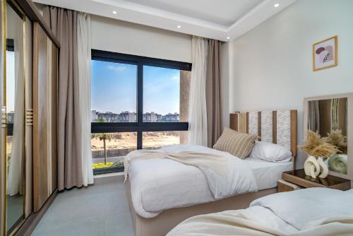 a bedroom with two beds and a large window at Luxury Smart Home Entire Apartment with 2 Bedrooms in Madinaty in Madinaty