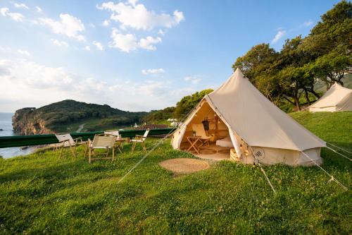 a tent in the grass next to the water at Kampaoh Las Arenas in Pechón