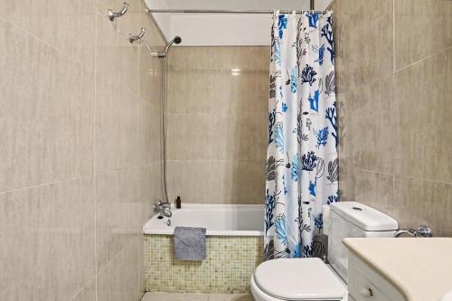 a bathroom with a toilet and a shower curtain at Los Cristianos Plaza Centre suite in Los Cristianos
