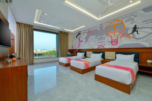 a hotel room with three beds and a mural at Ginger Gadchiroli in Garhchiroli