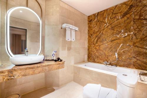 a bathroom with a sink and a tub and a mirror at Fox Hotel Nagoya Batam in Nagoya