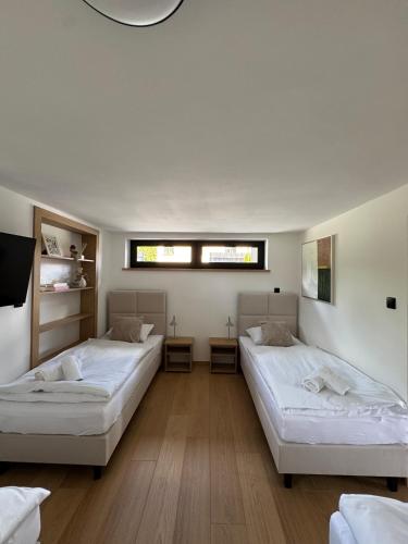 two beds in a room with white walls and wooden floors at Willa Black Wood in Istebna