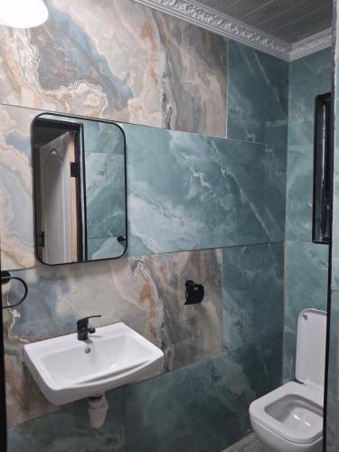 a bathroom with a sink and a mirror and a toilet at Jacaranda Bnb in Khayelitsha