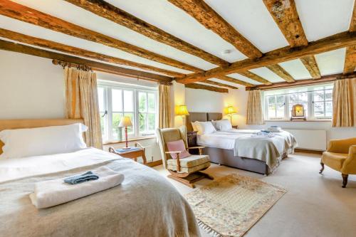 a bedroom with two beds and a chair and windows at 5 Bed in Magham Down oc-sx942 in Hailsham