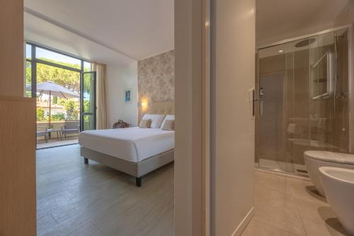a bedroom with a bed and a bathroom at Hotel Acapulco in Forte dei Marmi