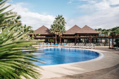 a swimming pool with chairs and a resort at Camping Estival Torre de la Mora in Tamarit
