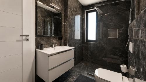 a black tiled bathroom with a sink and a toilet at Art Suite - Private Parking in Oradea