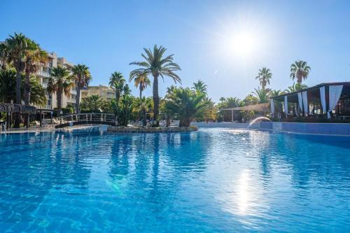 a large swimming pool with palm trees in a resort at Estival Islantilla in Islantilla