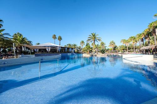 a swimming pool at a resort with palm trees at Estival Islantilla in Islantilla