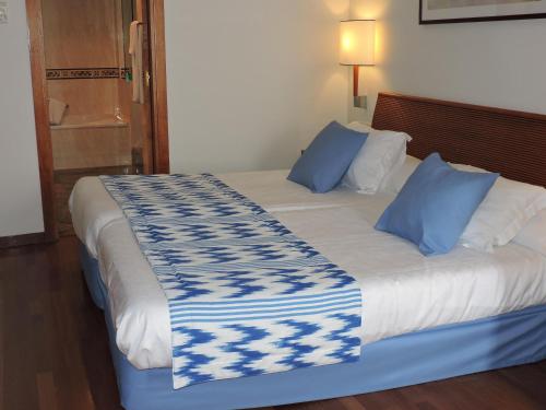 a bed with blue and white sheets and blue pillows at Estival Park Silmar in La Pineda