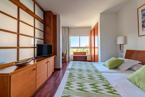 a hotel room with a bed and a flat screen tv at Estival Park Silmar in La Pineda