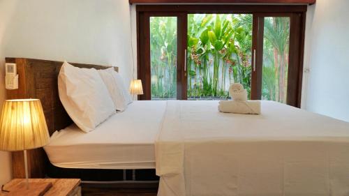 a bedroom with a large white bed with a window at Kubu Kiku Megati in Selemadeg