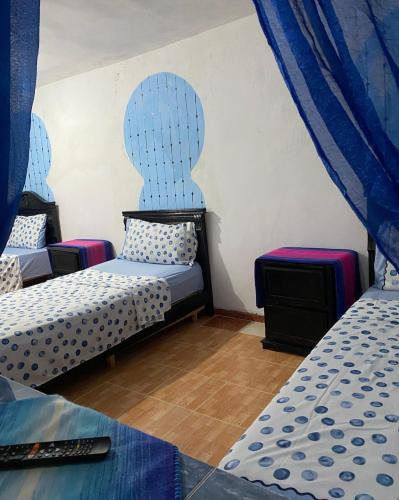 two beds in a room with blue curtains at Bleu Chefchaouen in Chefchaouen