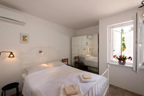 a white bedroom with a bed and a window at Apartment Pasarela in Gajac