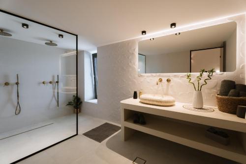 a white bathroom with a sink and a shower at Ios Sea view apartment with pool 2B in Ios Chora