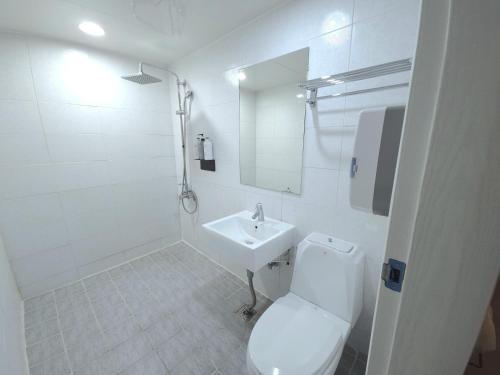 a white bathroom with a toilet and a sink at AREA HoTEL in Yeongju