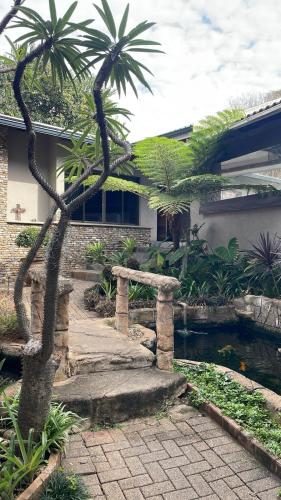 a palm tree in front of a house with a pond at Bee Boutique Lodge in Nelspruit