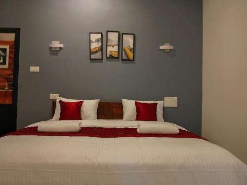 a bedroom with a large bed with red and white pillows at Seabay Bliss Varkala by Ojes in Varkala