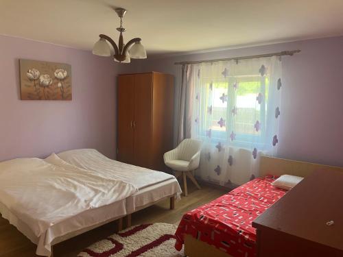 a bedroom with a bed and a window and a chair at Aranykéz vendégház in Şoimeni