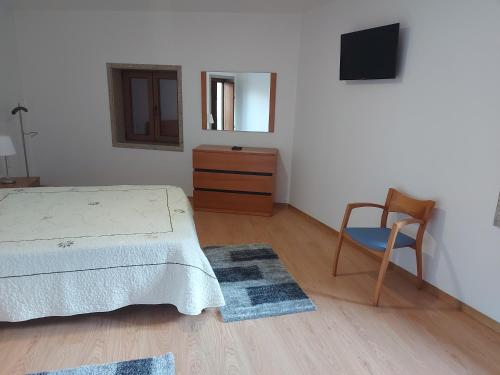 a bedroom with a bed and a chair and a dresser at Casa Novelhos in Penafiel