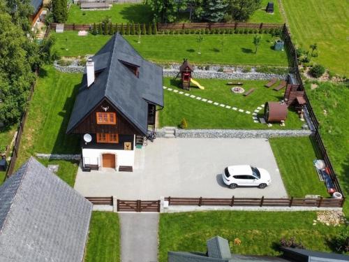a small house with a car parked in the yard at Traditional deer Cabin with Sauna - Chata Srňacie in Dolný Kubín
