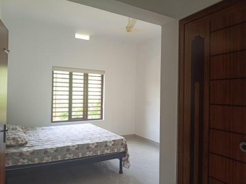 a white room with a bed and a window at Ithal Villa - Home Stay in Wayanad