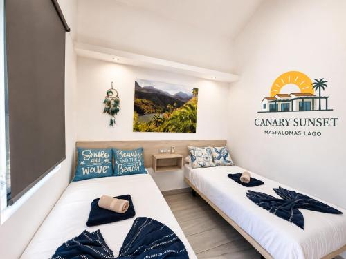 a bedroom with two beds and a sign that readsancy sunset at Maspalomas Lago Canary Sunset in Maspalomas