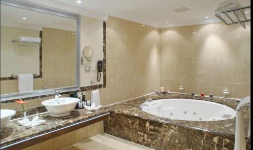 a bathroom with a tub and a large mirror at Porto Matrouh Hotel in Marsa Matruh