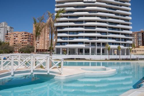 a swimming pool with a large building in the background at Benidorm Beach Belluba luxury bay in Benidorm