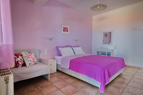 a bedroom with a pink bed and a couch at Ikos Studios and Apartments in Patitiri