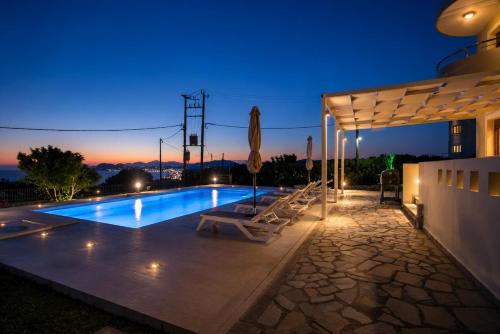 a swimming pool with a table and a umbrella at Villa Kallithea Sunrise in Koskinou