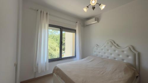 a white bedroom with a bed and a window at Viluni Coast Apartment in Velipojë