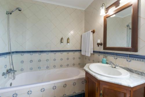 ein Badezimmer mit einer Badewanne, einem Waschbecken und einem Spiegel in der Unterkunft Azor Beach Lodge in Ponta Delgada