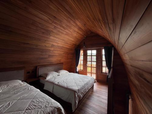 two beds in a room with wooden walls at Better House & Cabin Dieng in Diyeng