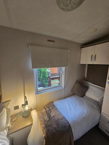 a small bedroom with a bed and a window at Chillingham lodge with hot tub Felmoor Park in Felton