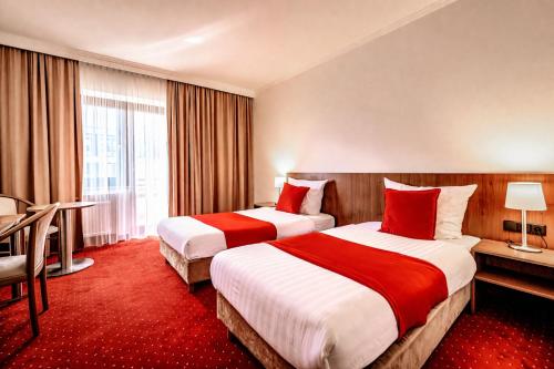 two beds in a hotel room with a red carpet at REDBERRY Hotel - Düsseldorf - Neuss in Neuss