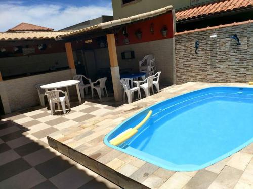 ein Pool mit Stühlen und ein Tisch neben einem Haus in der Unterkunft CASA DUPLEX - ARRAIAL DO CABO (Monte Alto) in Arraial do Cabo