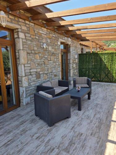 a patio with couches and a table and a stone wall at Alyki Stone House 3 in Alyki