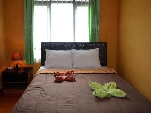 a bed with two towels and two dolls on it at Dajan Buyan Homestay in Bedugul