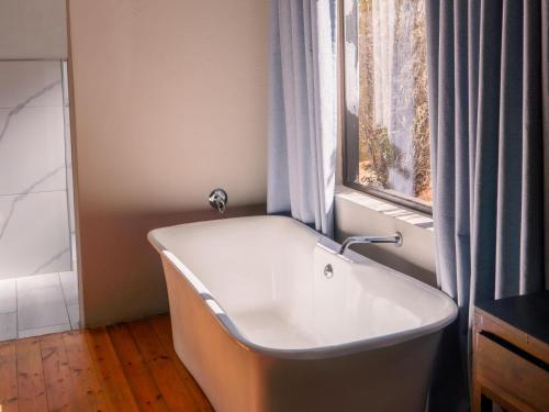 a bath tub in a bathroom with a window at Stay Local Potchefstroom in Potchefstroom