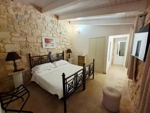 a bedroom with a bed and a stone wall at Borgo Hedone in Scicli