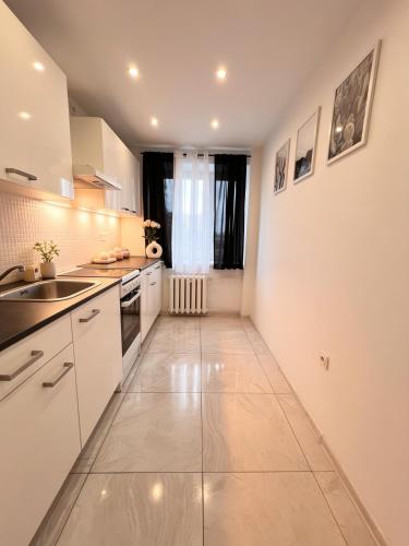 a kitchen with white cabinets and a sink and a window at Apartament w Centrum Prudnika in Prudnik