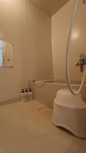 a white bathroom with a toilet and a tub at Bears Cottages in Furano